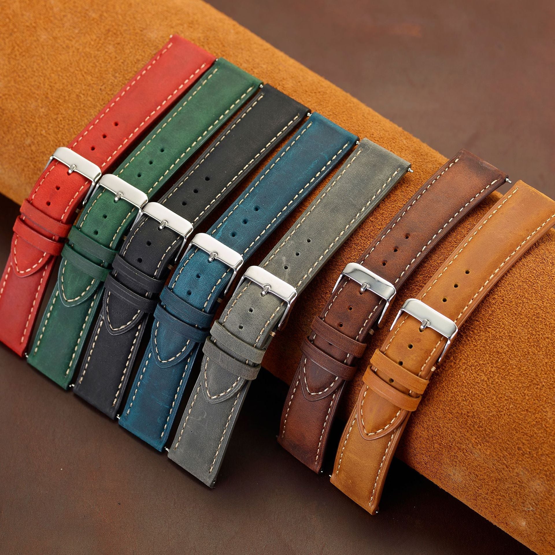Sieben Vintage-Lederbänder in Rot, Grün, Schwarz, Blau, Grau und Brauntönen auf einer Lederunterlage